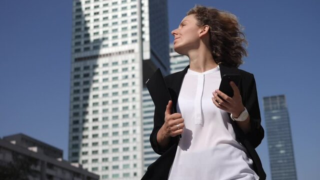 Stressed business woman walking in front of skyscrapers