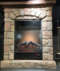 Electric fireplace with decorative firewood and fire. Hearth with fire indoors. Room heater in winter.