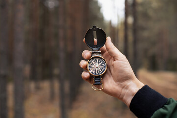 Compass in man's hand on forest background