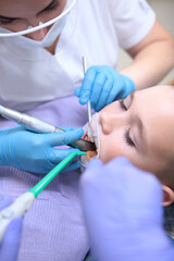 A little boy at a dental clinic reception. The dentist cleans the teeth of a small patient. Professional teeth cleaning. The concept of health. Vertical photo.