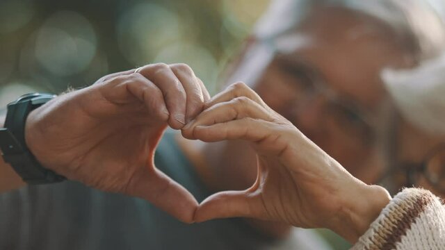 Older retired couple making heart with their hands. Selective focus. High quality 4k footage