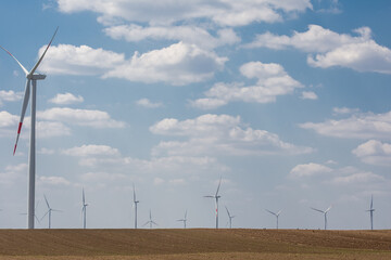 Wind turbines and agricultural field on a summer day. Energy production, clean and renewable energy.