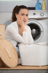 fed-up woman sitting by the laundry basket
