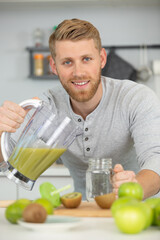 Fototapeta premium handsome man make fresh juice smoothie from apple and kiwi