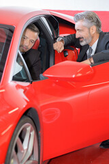 happy man showing key of new red sports car