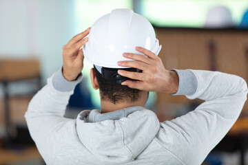 workman adjusting his hard hat to fit correctly