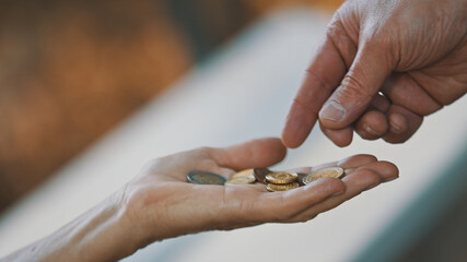 Close up, man hand giving coins to elderly homeless woman. Charity and support concept. High quality photo