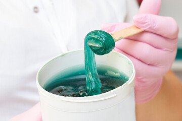 Liquid sugar for skin epilation. Close shot. cosmetologist holding a jar of sugar paste for depilation.