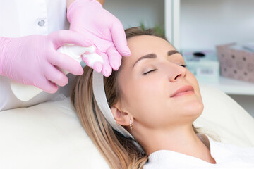 Obraz na płótnie Canvas cosmetology. Close up picture of lovely young woman with closed eyes receiving facial cleansing procedure in beauty salon.