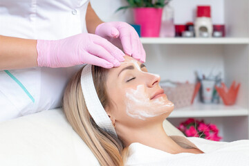 Naklejka premium cosmetology. Close up picture of lovely young woman with closed eyes receiving facial cleansing procedure in beauty salon.