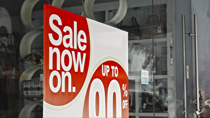 Red round sign hanging on a glass window with the inscription sale now on up to 90% off