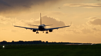 Fototapeta na wymiar Airplane Landing on a runway at dusk