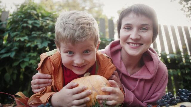 Volunteer lesbian playing with boy orphan preparing carved pumpkin for Halloween party. Fall background.