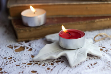 Burning small candles on the background of old shabby books, autumn, comfort concept