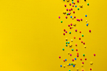 on a bright yellow background confectionery patch of rainbow colors, confetti, rainbow, stars