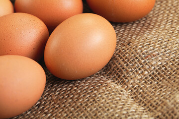 Beige coloured eggs on jute textile cloth, closeup detail, space for text right down corner