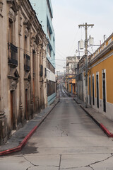 Fototapeta na wymiar Narrow empty street of colonial city early in the morning on a cloudy day - street of historic center of Quetzaltenango Guatemala
