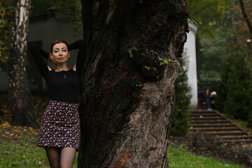 Pretty woman standing near an old tree in the park