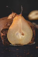 Homemade vegan chocolate cake with poached pears placed on the dark background.
