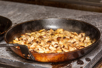 Wild mushrooms are fried in a frying pan in a restaurant