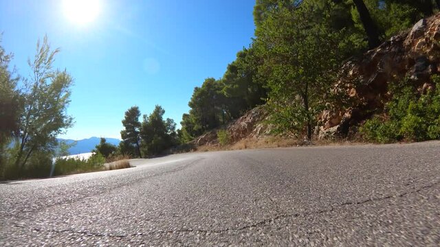 Time Lapse video of forest curvy road taken by stabilised camera attached to motorcycle as seen from lowest possible asphalt perspective 