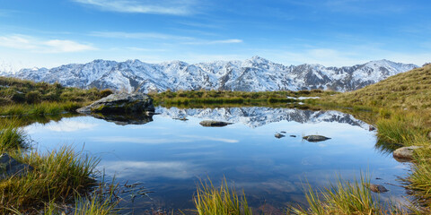 Fototapeta na wymiar Panorama eines Sees in den Alpen mit verschneiten Bergen im Hintergrund