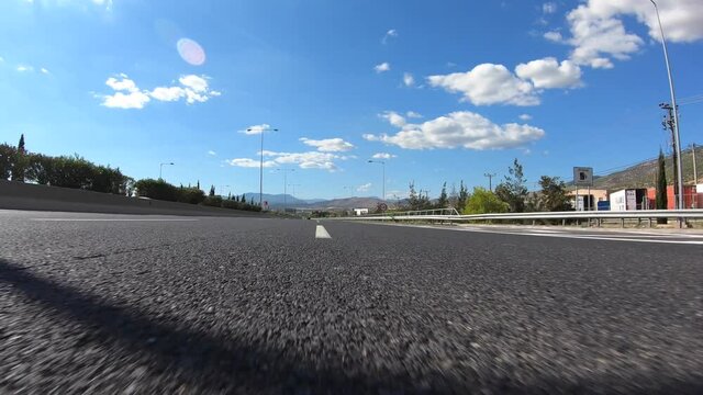 Fast moving video of national road with with clear blue skies taken by stabilised camera attached to motorcycle as seen from asphalt road perspective 