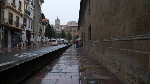 A gray and rainy day in the old town, people with umbrellas walk down the street