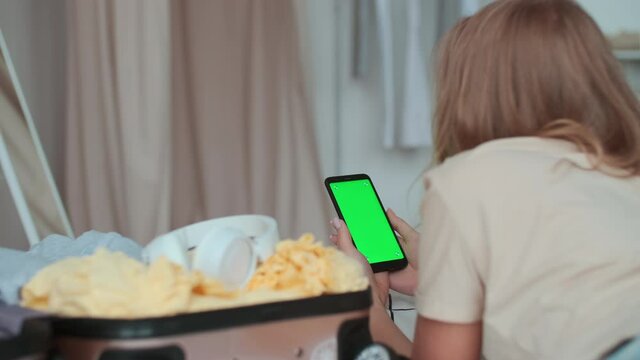 Green screen template, Chroma Key, Touchscreen Display, Open Borders, Booking Hotel. Woman swipes her finger from bottom to top on smartphone display
