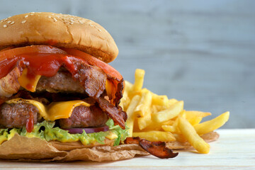 Delicious fresh Burger with double cutlet and French fries on a light background