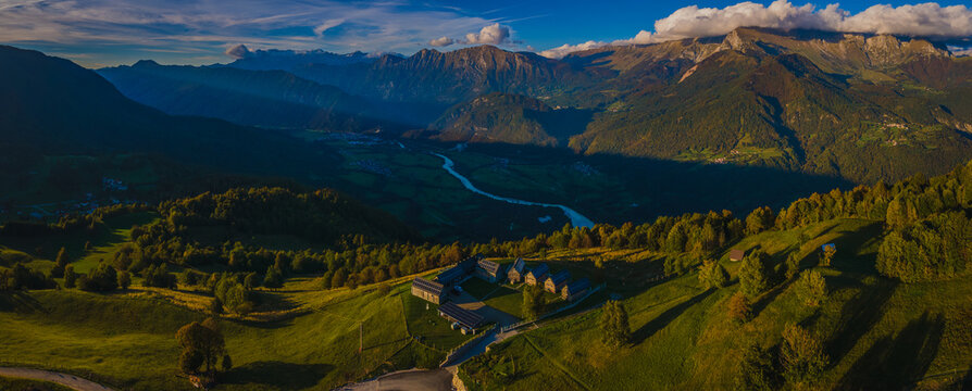 Panorama from Kolovrat mountain down towards Soca valley and Kobarid. Dark and cold Soca valley opposed to sunlit mountains above it.
