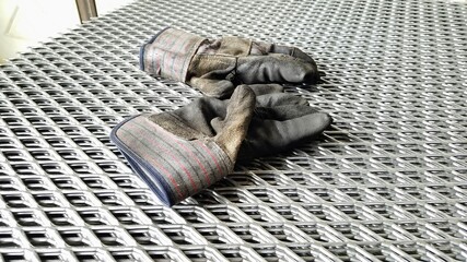 Work gloves on top of expanded sheet metal.