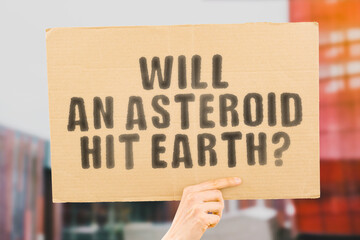 The question " Will an asteroid hit earth? " on a banner in men's hand with blurred background. Cataclysm. Apocalypse. Dangerous. Prognosis. Science. Solar system. Hazardous