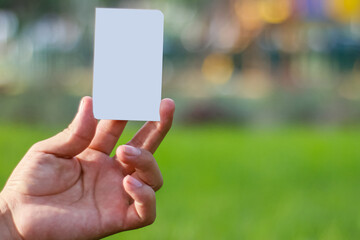 Businessman hand holding business card isolated on unfocused background in green area of ​​a park.