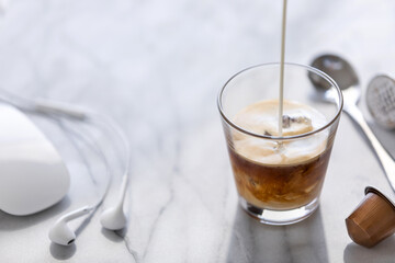Pouring cream into an iced espresso in a glass. Copy space.