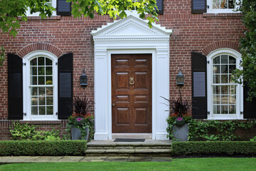 Elegant wooden front door of  traditional brick two story suburban middle class home