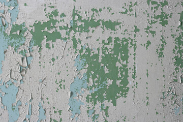 Peeling paint on the wall. Old concrete wall with cracked flaking paint. Weathered rough painted surface with patterns of cracks and peeling. High resolution texture for background and design. Closeup