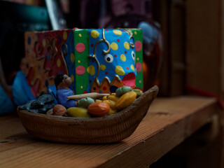 Gifts upon returning from a trip to Thailand. Two wooden souvenirs, a fisherman on a boat with fruit in the background of a large colorful fish.