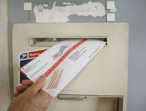 ATLANTA, GEORGIA - OCTOBER 9, 2020 : Absentee voter mailing vote by mail ballot at a U.S. Post Office mailbox.