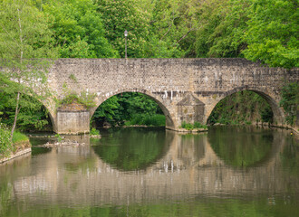 Fototapeta na wymiar Eine alte Steinbrücke spiegelt sich im Wasser