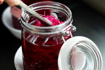 Reaching for bright pink sauerkraut pickles from inside jar