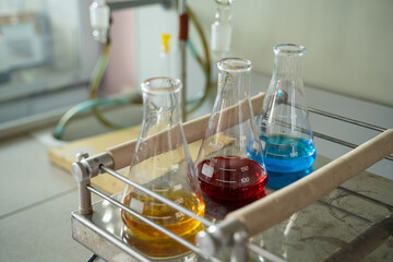 Row of three erlenmeyer flasks with multicolored liquids in it in a lab