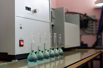 Row of volumetric flasks on a laboratory table with blue liquid inside