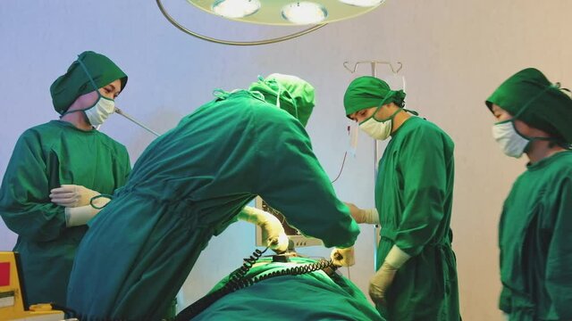 Asian medical team doctor and nurse in uniform giving electric cardiopulmonary resuscitation (CPR) to critical patient in emergency room in hospital, resuscitation and defibrillation concept