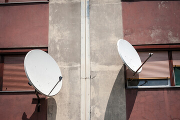 Satellite dish and  and TV UHF antennas on display at the top of a residential building. These are used for communications and satellite television reception