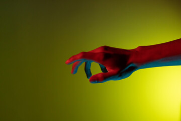 Antebrazo y mano color rojo y azul en fondo amarillo