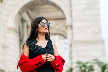 Attractive young woman wearing black sunglasses and red coat. Outdoor shot. Beauty and fashion concept.