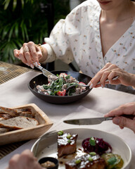 People elegantly eating gourmet meals in a restaurant, daylight photo, hands only visible