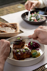 People elegantly eating gourmet meals in a restaurant, daylight photo, hands only visible