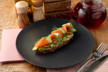 Whole grain rye bruschetta with cream cheese, vegetables and smoked salmon on a long slice of grilled crunchy toast